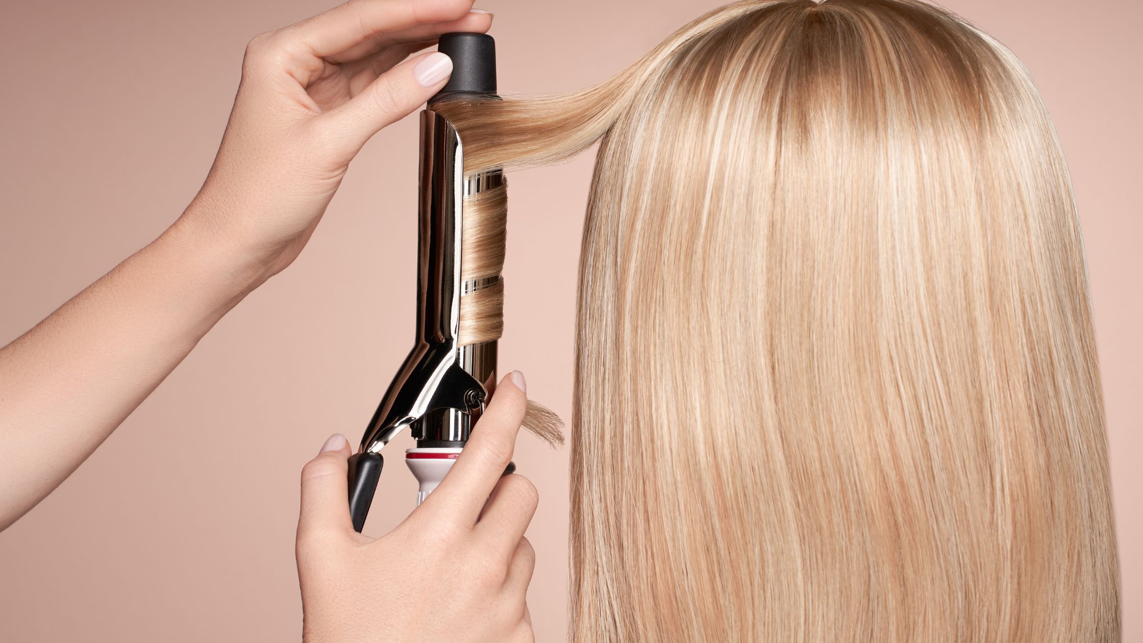 Hairdresser using curling iron on customer's hair